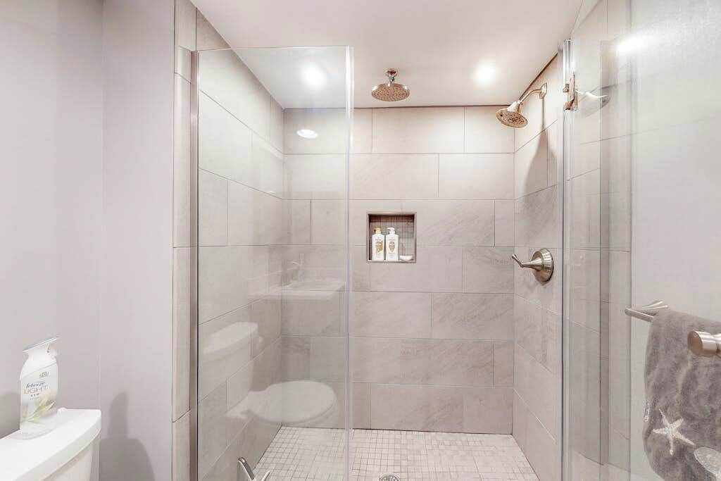 Et moderne badeværelse med bruseniche, toilet og håndklædestang.