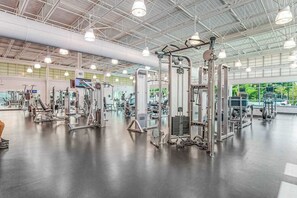 A gym with various exercise machines, large windows, and a high ceiling. - Sea Colony tennis condo with pools, fitness center & tennis courts (Bethany Beach)