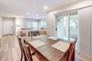 A dining area with a wooden table, chairs, and a sofa. - Sea Colony tennis condo with pools, fitness center & tennis courts (Bethany Beach)