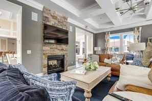 A living room with a fireplace, a television mounted on the wall, a sofa, and a coffee table. - Bishops Landing townhome with private washer/dryer, shared pool, tennis, gym (Millville)