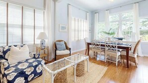 Un salon comprenant un canapé, des fauteuils, une table à manger et donnant sur l’extérieur.