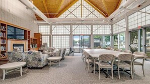 Une pièce spacieuse avec une grande table, des chaises, des canapés et une cheminée.