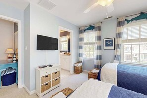 A bedroom with a bed, a TV, a dresser, a window with curtains, and a door leading to another room. - Bear Trap Dunes home with fabulous shared amenities, jetted tub, & bikes (Ocean View)