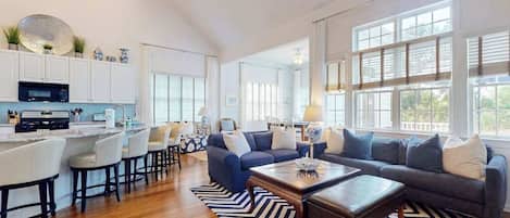 A spacious living area with a kitchen, a dining area, and a large window providing natural light.