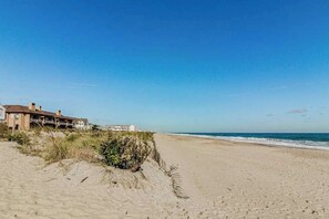 A beach with a building on the left, sandy beach, and ocean. - Enchanting condo w/ ocean-view, with balcony, pool, washer/dryer, & dog-friendly (Dewey Beach)