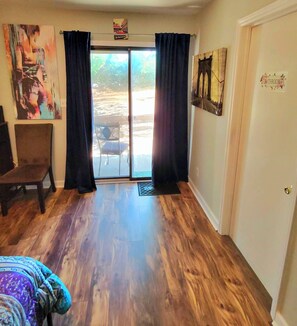 Ein Zimmer mit Holzboden, einem Sessel, einem Bett und einer Tür mit der Aufschrift 'Bad'.