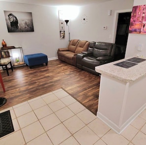 Ein Wohnzimmer mit einem braunen Ledersofa, einem blauen Hocker, einem Couchtisch und einer Wanduhr.
