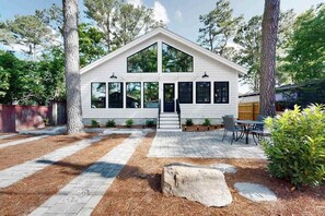 A modern house with a white exterior, large windows, and a stone pathway leading to the entrance. - Town of Dewey Beach modern home with grill & outdoor showers - prime location (Dewey Beach)