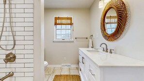Baño con ducha, inodoro, lavabo y ventana con persianas.