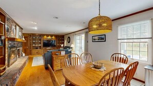 Un vaste espace de vie agrémenté d’une cheminée, d’une table à manger en bois et de sièges confortables.