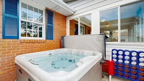 A hot tub in a covered outdoor area with a brick wall, a window with blue shutters, and a pool table. - Town of Dewey Beach house near golf with fireplace & fenced yard - dog-friendly (Dewey Beach)