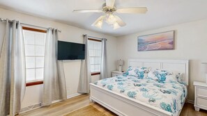 A bedroom with a bed, a ceiling fan, a TV, and a painting on the wall. - Town of Dewey Beach house near golf with fireplace & fenced yard - dog-friendly (Dewey Beach)