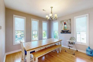 A dining room with a wooden table, bench, and high windows. - Spectacular pet friendly house walk to beach w/ocean views, private pool (Dewey Beach)