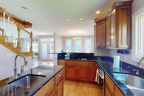 A spacious kitchen with wooden cabinets, granite countertops, and a built-in island. - Spectacular pet friendly house walk to beach w/ocean views, private pool (Dewey Beach)