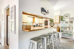 Eine moderne Küche mit Holztischplatte, Barhocker und einer Wanddekoration mit einem Walmotiv.