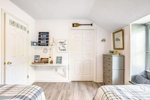 Ein Schlafzimmer mit zwei Betten, einem Schminktischchen, einer Kommode und einer Tür mit einer Baseballschläger-Dekoration.
