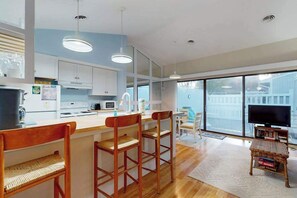 A modern kitchen with white cabinets, a wooden bar area with stools, a large window, and a television. - Sea Colony Tennis 1st floor condo w/ pool, free WiFi, and gym (Bethany Beach)