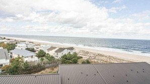 Eine Küstenansicht mit Strand, Häusern und bewölktem Himmel.