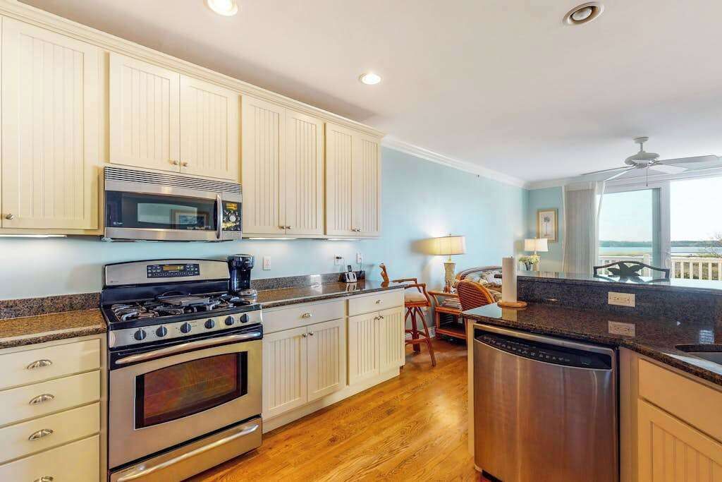 A kitchen with white cabinets, stainless steel appliances, and a wooden floor.