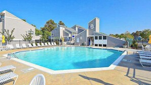 Una piscina con sillones de descanso y un área techada.