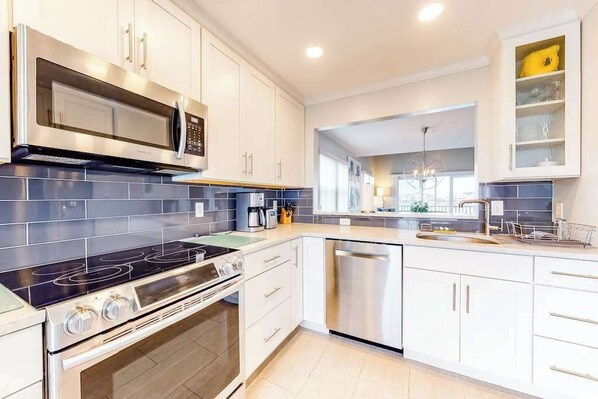A modern kitchen with white cabinets, a stainless steel microwave, a gas stove, and a dishwasher. - Bethany Bay Third-Floor Condo with Pool, Tennis Court, & Board Games (Ocean View)