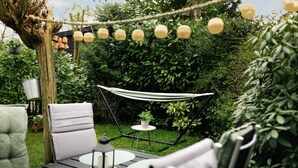 A garden with a hammock, a table with a candle, and a hanging light fixture. - Veluwse Oase | Sfeervol chalet op park de IJsvogel (Voorthuizen)