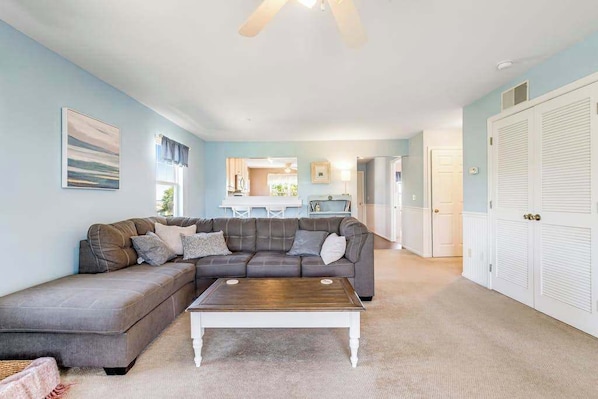 A living room with a sectional sofa, a coffee table, and a ceiling fan.