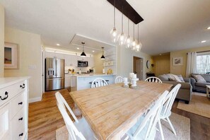 Eine moderne Küche mit weißen Schränken, einem Holzespeisetisch und hängenden Pendelleuchten.
