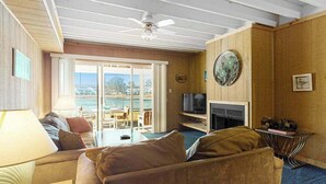 Ein Wohnzimmer mit Sofa, Fernseher, Kamin und Blick durch eine Glastür.