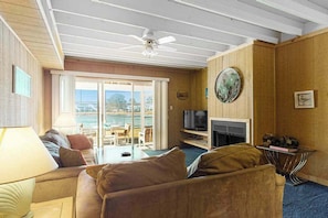 A living room with a sofa, a television, a fireplace, and a view through a glass door.
