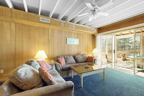 A room with two sofas, a coffee table, and a ceiling fan.