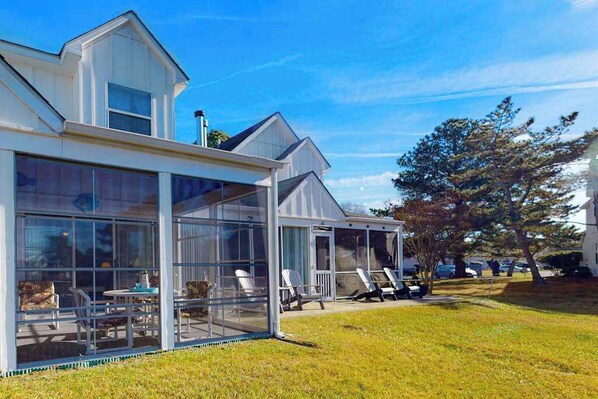 A modern house with a large glass extension, outdoor seating, and a well-maintained lawn. - Mallard Lakes Home w/Beautiful Water Views From Screened-In Porch, Shared Pool, WD (Selbyville)