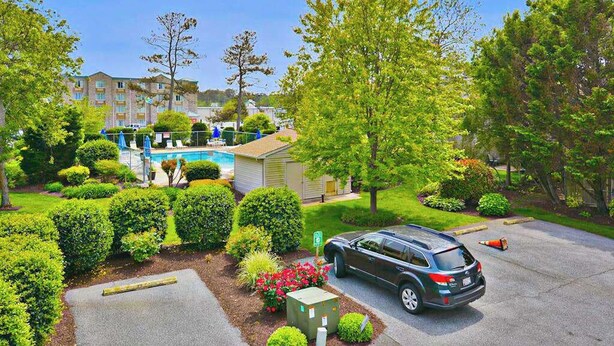 A residential area with a swimming pool, a car, and neatly trimmed bushes. - Sea Pines Townhouse Steps From the Water w/Free WiFi, Shared Pool, Private W/D, AC (Bethany Beach)