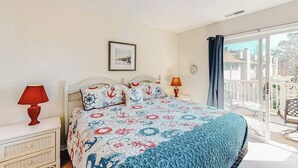 A bedroom with a bed, two bedside tables, a window, and a balcony. - Sea Pines Townhouse Steps From the Water w/Free WiFi, Shared Pool, Private W/D, AC (Bethany Beach)