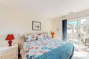 A bedroom with a bed, two bedside tables, a window, and a balcony. - Sea Pines Townhouse Steps From the Water w/Free WiFi, Shared Pool, Private W/D, AC (Bethany Beach)