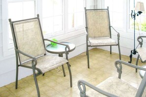 A room with four metal-framed chairs with cushioned seats and backs, arranged around a small round table with a green object on it. - Town of Bethany Beach Retreat w/Private Washer/Dryer & Free WiFi (Bethany Beach)