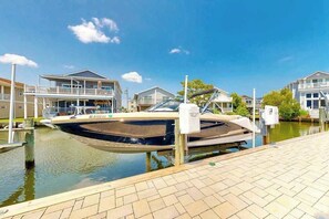 A marina with a boat docked, a building with a balcony, and a clear sky. - Town of Fenwick island home on the water with dock & central A/C - dogs OK (Fenwick Island)