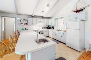 A modern kitchen with white cabinetry, a central island with a sink, and a refrigerator.
