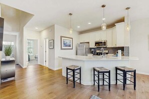 A modern kitchen with a central island, pendant lighting, and a view to the adjacent living area. - Bear Trap Dunes home with washer/dryer, WiFi, pool, & sauna - near golf (Ocean View)