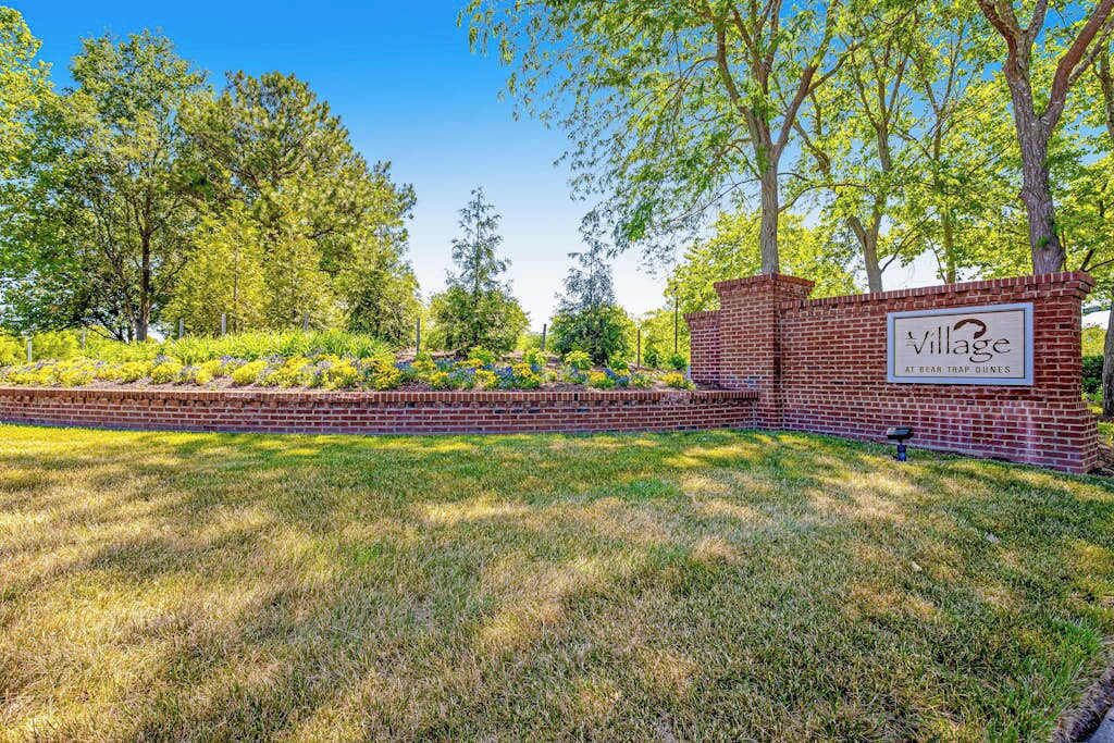 A brick wall with a sign reading 'Village at Bear Trap Dunes.'