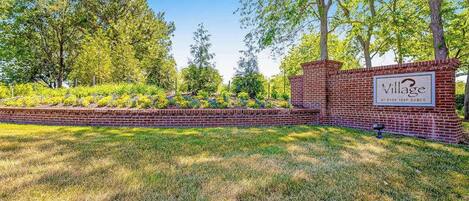 A brick wall with a sign reading 'Village at Bear Trap Dunes.'