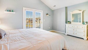 Un dormitorio con cama, cómoda, ventilador de techo y balcón con vistas.