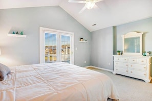 Ein Schlafzimmer mit Bett, Schminktisch, Deckenventilator und einem Balkon mit Blick.