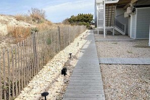A wooden deck leading to a house with a garage, surrounded by a wooden fence and a gravel path.