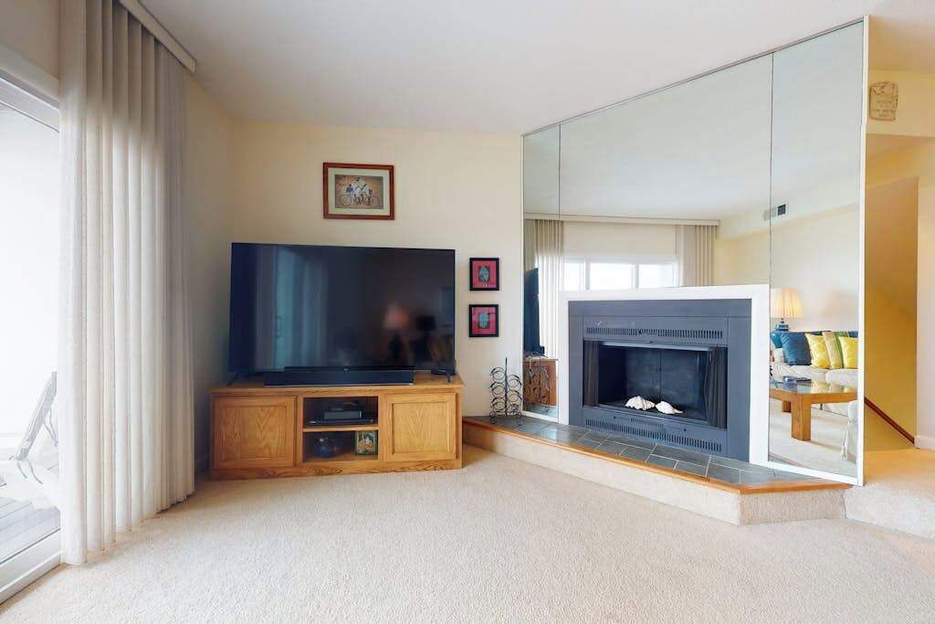 A living room with a television, fireplace, and a large mirror reflecting the room.