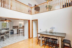 A spacious open-plan living area with a dining table, bar stools, and a staircase leading to an upper level. - Lovely home near the ocean, w/ fire pit, tiki bar, washer/dryer, WiFi, & Netflix (Selbyville)