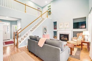 Ein Wohnzimmer mit Treppe, Kamin, Sofa und Fernseher.
