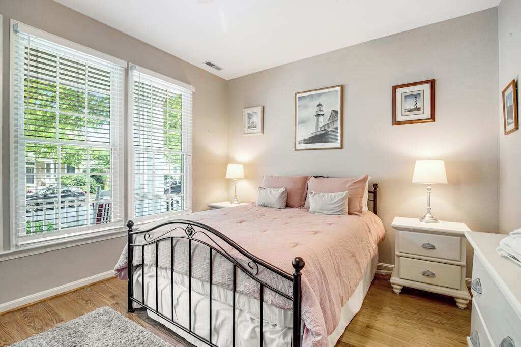 A bedroom with a bed, bedside tables, and a window with blinds.