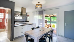 A modern kitchen with a dining area, large windows, and a view of the outdoors. - Gîte Le Grand Chêne: Shared Pool, Wi-Fi & Air Conditioning in Lesperon (Lesperon)