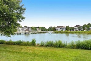 A residential area with houses, a lake, and a wooden dock. - Bethany Lakes home with waterfront views, pool access, tennis, & private patio (Bethany Beach)